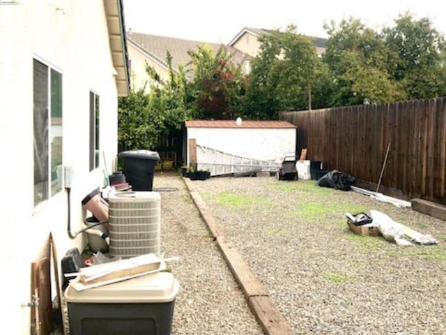 view of yard featuring a storage shed and central air condition unit