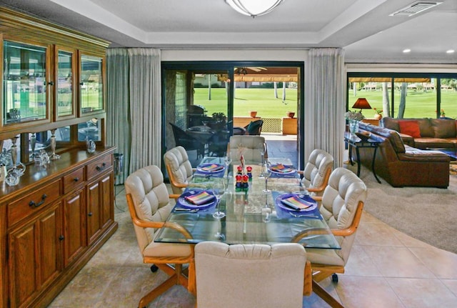 dining area with a tray ceiling, plenty of natural light, and light tile patterned floors