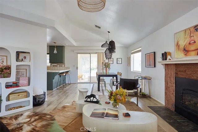 living room with light hardwood / wood-style flooring, a healthy amount of sunlight, and lofted ceiling