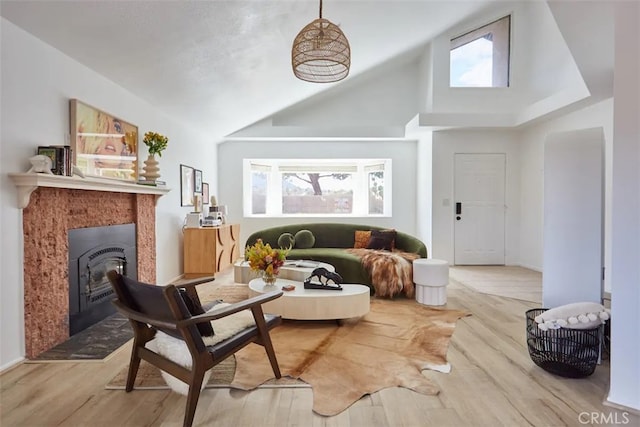 sitting room with high vaulted ceiling, a glass covered fireplace, and wood finished floors