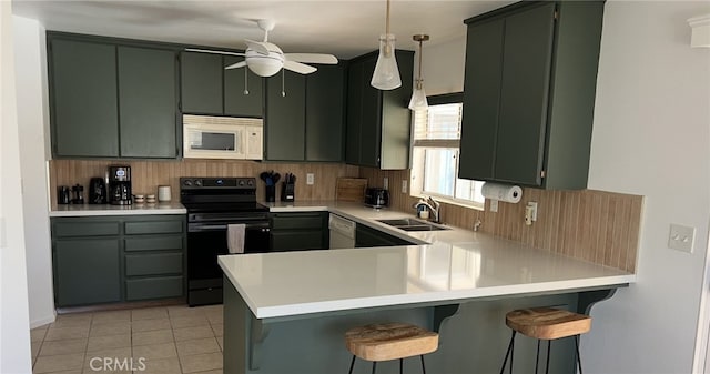 kitchen featuring white appliances, a peninsula, a sink, light countertops, and green cabinetry