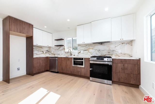 kitchen with backsplash, light wood-type flooring, white cabinetry, and stainless steel appliances