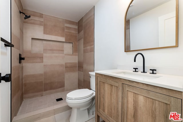 bathroom with tile patterned floors, vanity, toilet, and tiled shower