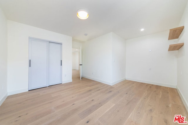 unfurnished bedroom featuring light hardwood / wood-style flooring and a closet