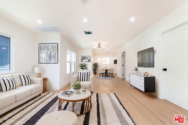 living room featuring a chandelier and light wood-type flooring