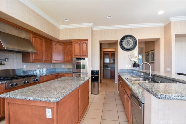 kitchen with light stone countertops, appliances with stainless steel finishes, wall chimney exhaust hood, crown molding, and sink