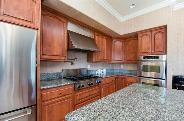 kitchen featuring stone counters, crown molding, wall chimney range hood, and appliances with stainless steel finishes