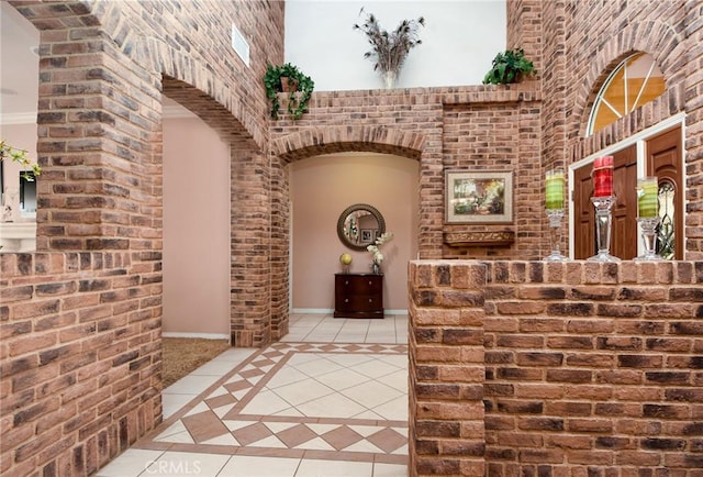 interior space featuring light tile patterned floors, crown molding, and a towering ceiling