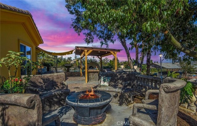 patio terrace at dusk featuring an outdoor living space with a fire pit