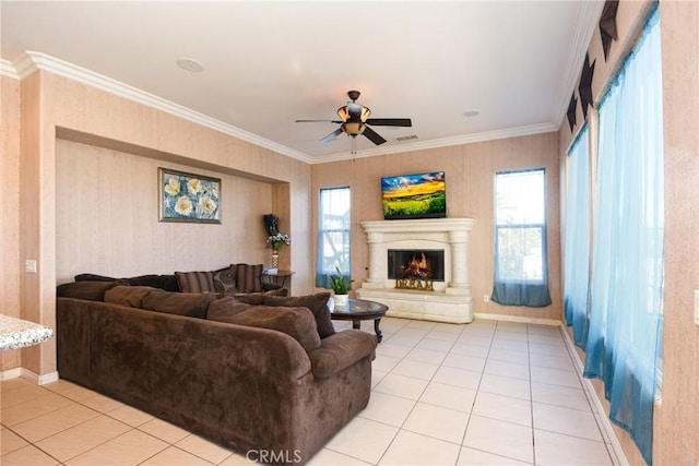 living room with a wealth of natural light, crown molding, ceiling fan, and light tile patterned floors