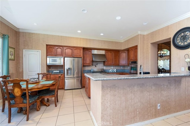 kitchen with wall chimney range hood, crown molding, light tile patterned floors, appliances with stainless steel finishes, and light stone counters