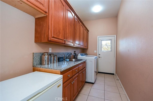 laundry area with cabinets, washer / dryer, light tile patterned flooring, and sink