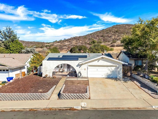 ranch-style house with a garage, a mountain view, and solar panels