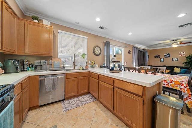 kitchen featuring sink, tile countertops, kitchen peninsula, appliances with stainless steel finishes, and ornamental molding