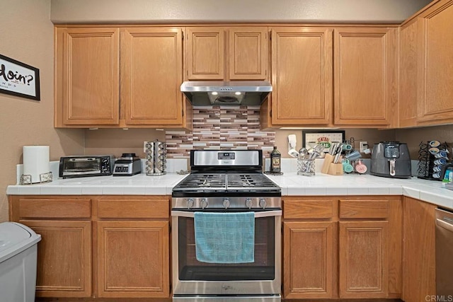 kitchen with backsplash, tile counters, and stainless steel gas range oven