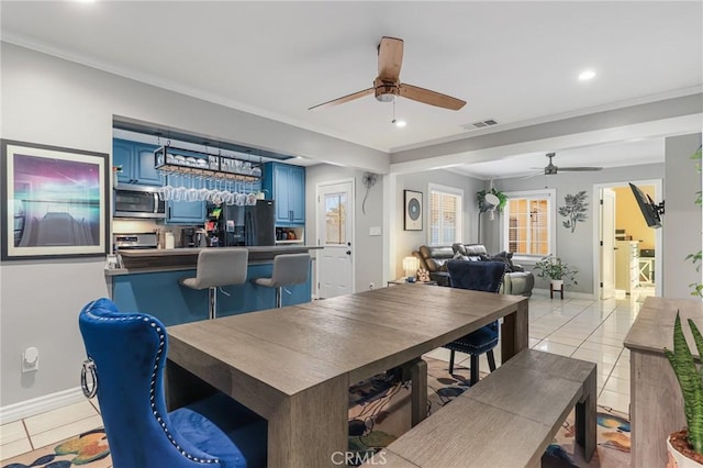 dining room with ceiling fan, crown molding, and light tile patterned floors