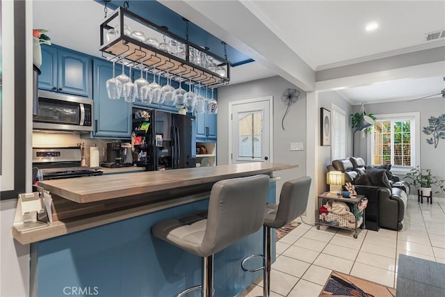 bar featuring stainless steel appliances, ornamental molding, light tile patterned floors, blue cabinetry, and backsplash