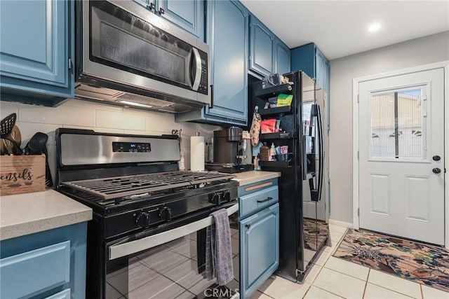 kitchen featuring appliances with stainless steel finishes, blue cabinets, tasteful backsplash, and light tile patterned floors