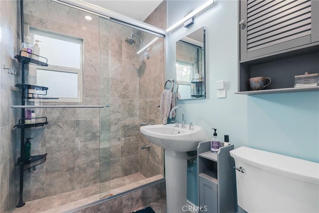 bathroom with a shower with door and toilet