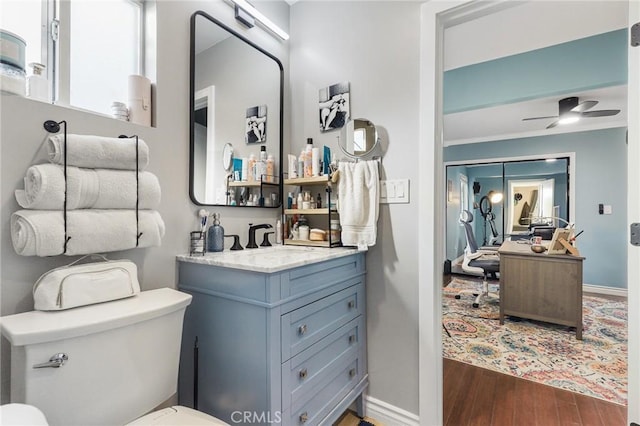 bathroom featuring ceiling fan, toilet, vanity, and hardwood / wood-style flooring