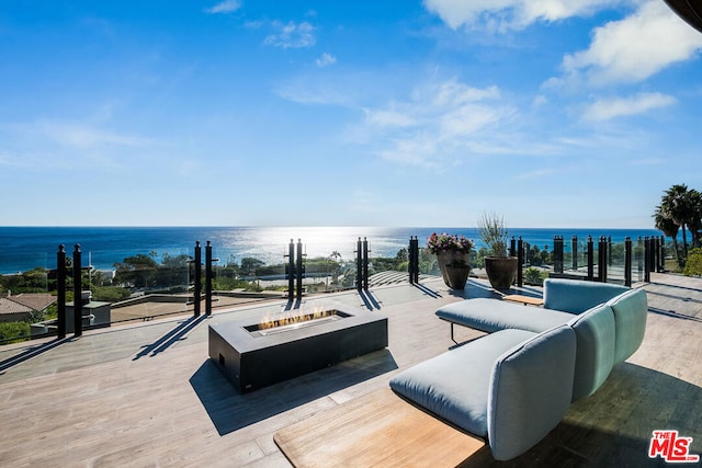 wooden terrace featuring a water view and a fire pit