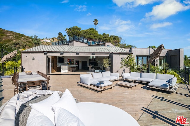 view of patio featuring outdoor lounge area, exterior bar, and a wooden deck