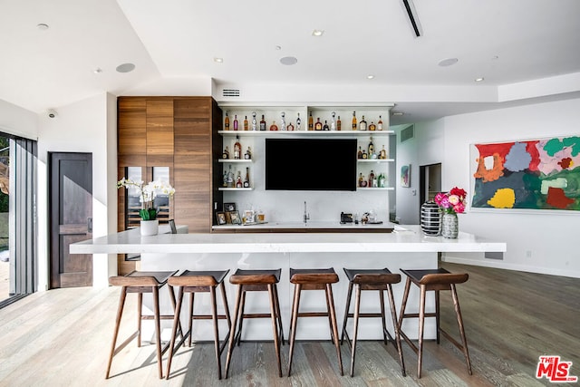 bar featuring a wealth of natural light, light hardwood / wood-style floors, and vaulted ceiling