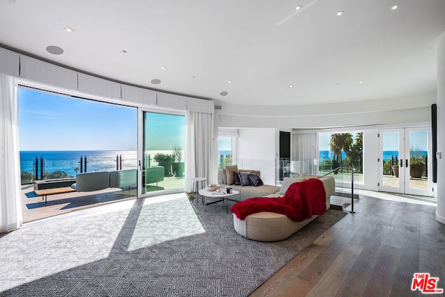 living room with hardwood / wood-style floors, a water view, a healthy amount of sunlight, and french doors