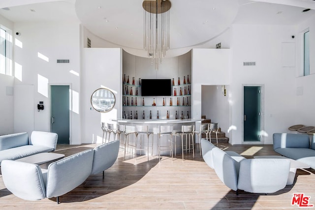 living room with bar, hardwood / wood-style floors, and a towering ceiling