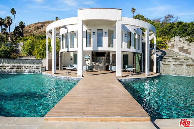 back of house with pool water feature, a balcony, a patio area, and an outdoor fireplace