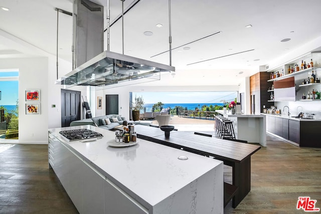 kitchen featuring dark hardwood / wood-style flooring, island range hood, a center island, and sink