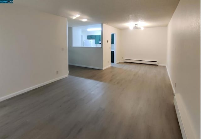 empty room featuring baseboard heating and wood-type flooring