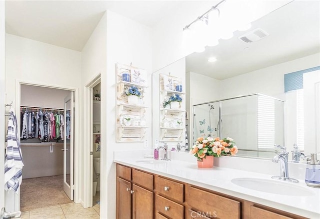 bathroom featuring tile patterned flooring, vanity, toilet, and a shower with shower door