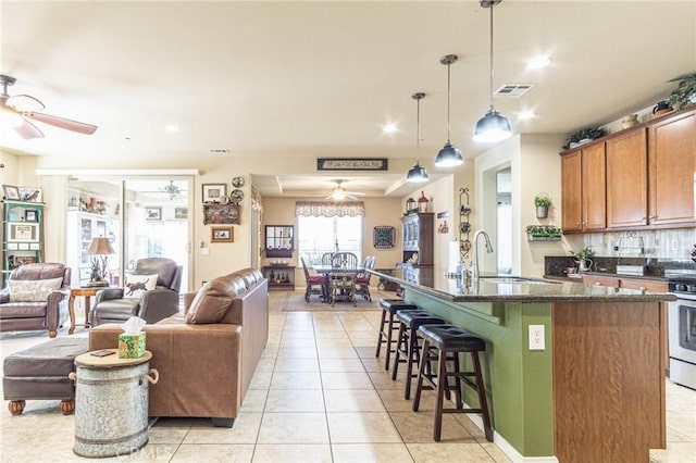 kitchen with a kitchen breakfast bar, sink, hanging light fixtures, light tile patterned floors, and an island with sink