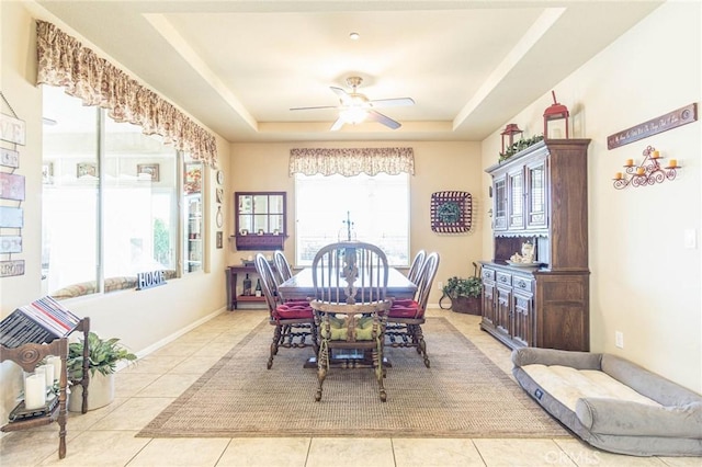 tiled dining room featuring a raised ceiling and ceiling fan