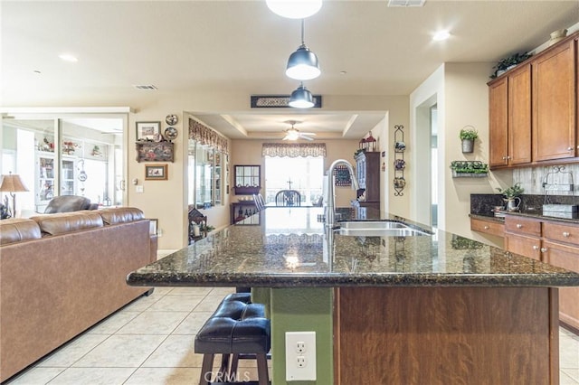 kitchen featuring ceiling fan, light tile patterned floors, sink, and a kitchen island with sink