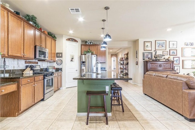 kitchen featuring pendant lighting, light tile patterned floors, an island with sink, and appliances with stainless steel finishes