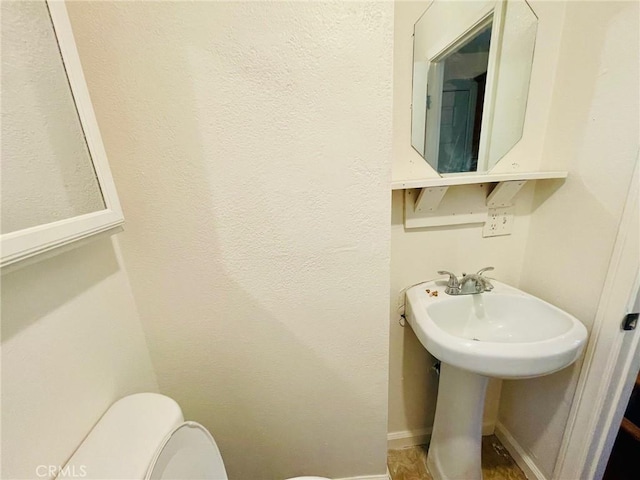 bathroom featuring baseboards, a sink, and toilet