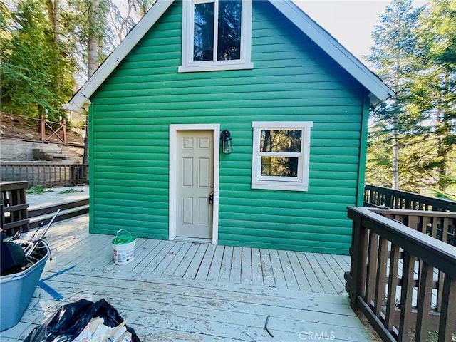 exterior space featuring faux log siding, a deck, and an outdoor structure