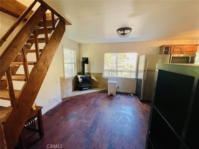 interior space with a wealth of natural light, dark wood-style flooring, baseboards, and a wood stove