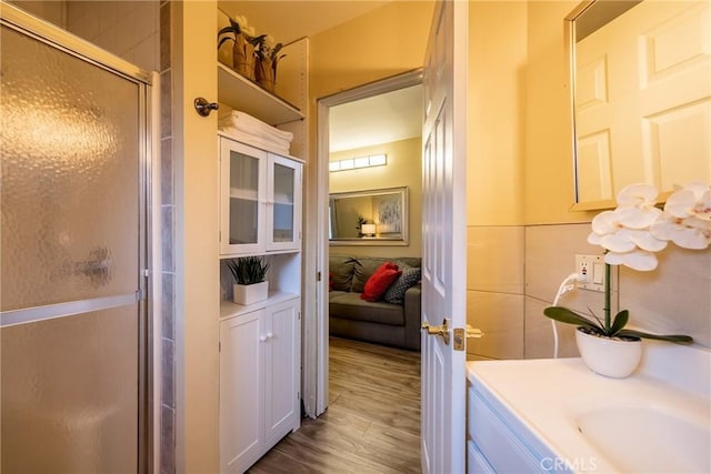 bathroom with a shower with shower door, wood-type flooring, and vanity