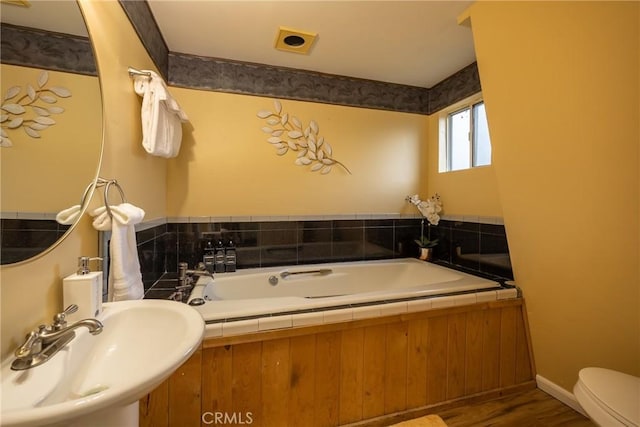 bathroom with hardwood / wood-style floors, toilet, a bathing tub, and sink