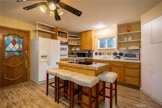 kitchen featuring backsplash, tile counters, light hardwood / wood-style floors, and white refrigerator with ice dispenser