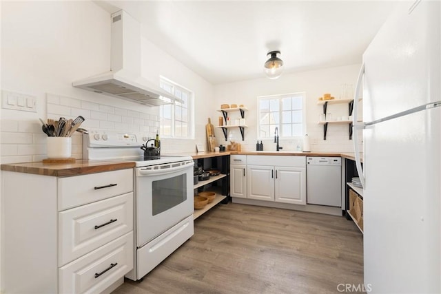 kitchen with wall chimney exhaust hood, white appliances, a wealth of natural light, and wooden counters