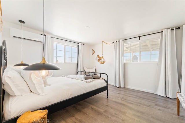 bedroom with hardwood / wood-style flooring and a wall mounted AC