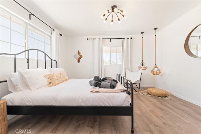 bedroom with hardwood / wood-style floors, an inviting chandelier, and multiple windows