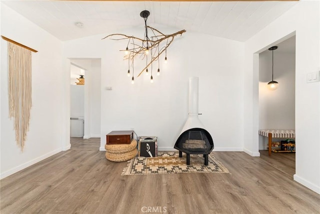 living area featuring hardwood / wood-style flooring, a chandelier, radiator, and vaulted ceiling