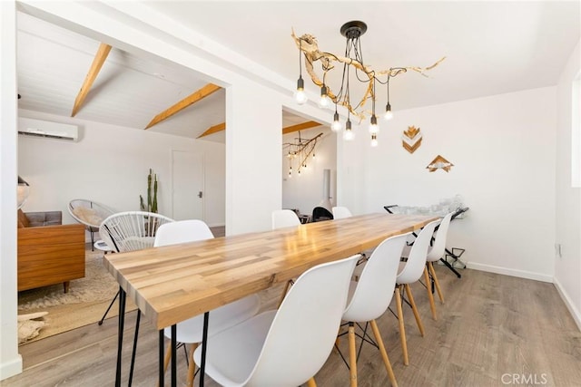 dining space with a wall mounted air conditioner, beam ceiling, light hardwood / wood-style floors, and a chandelier