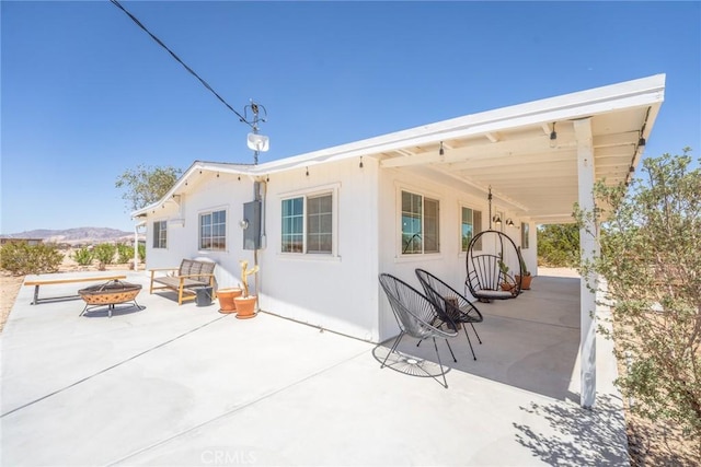 back of house featuring a mountain view, an outdoor fire pit, and a patio