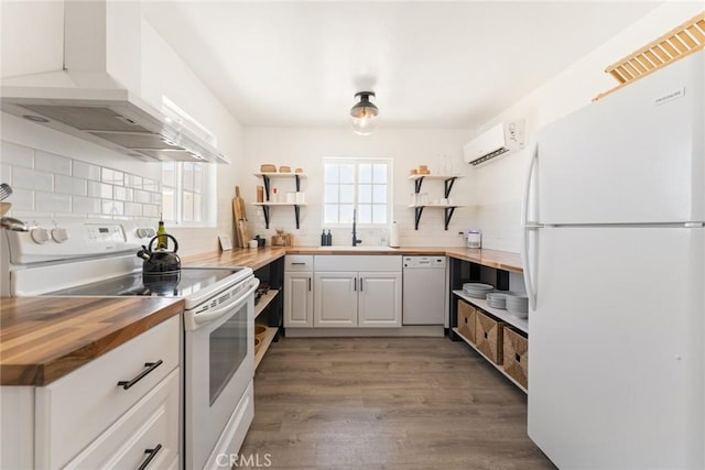 kitchen with butcher block counters, white cabinetry, an AC wall unit, light hardwood / wood-style floors, and white appliances